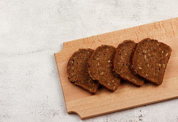 Slices of rye bread on a wooden cutting board on a light gray background. Top view, flat lay
