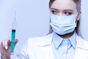 Close-up portrait of a doctor woman in a mask with a syringe in her hands. Isolated blue background. medicine and health concept