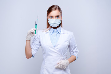 Female doctor in mask and gloves holding syringe on white isolated background