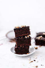 Chocolate brownie with nuts on paper on white background