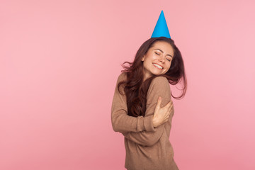 I love myself! Portrait of selfish beautiful young woman with long brunette hair wearing party cone...