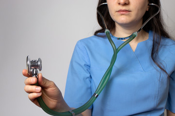 Doctor in blue uniform holds a stethoscope in his hand.