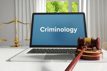 Criminology – Law, Judgment, Web. Laptop in the office with term on the screen. Hammer, Libra, Lawyer.