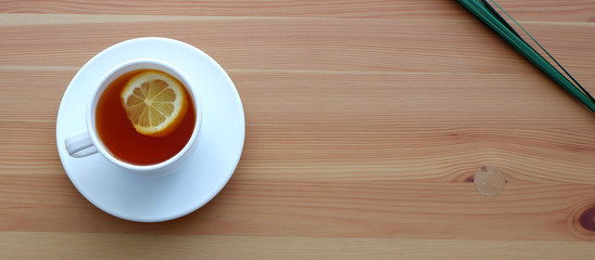 Mug with black tea and a slice of lemon on the table. Beautiful advertising background