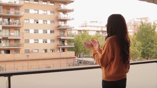 Video of a young woman applauding on the balcony in support of those who are fighting coronavirus