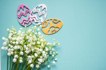 Floral blue background with fresh flowers. Spring greeting card for Easter. A bouquet of lily of the valley and a gift, eggs