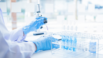 Medical or scientific researcher or man doctor looking at a test tube of clear solution in a...