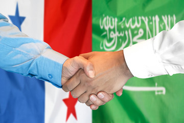 Handshake on Panama and Saudi Arabia flag background.