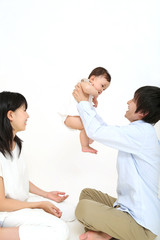 Fototapeta premium 若い夫婦が赤ちゃんを抱き上げ、子育てを協力している様子。