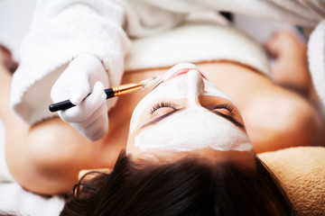 Woman getting spa face mask in beauty studio.