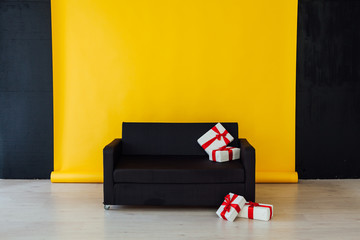 black sofa with gifts in the interior of the yellow room - obrazy, fototapety, plakaty