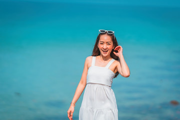 Fototapeta na wymiar girl in white dress and sunglasses a posing walking relax on the walkway bridge wood beach with sunlight shine and blue sky