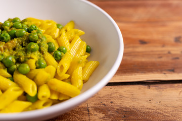 Creamy paste with green peas and saffron. Italian penne pasta for lunch. Summer food, fast lunch.