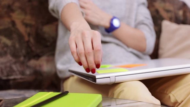  Focused female freelancer opening laptop and typing information. Young self-employed woman remotely working on internet projects from home.