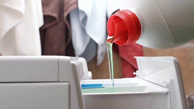 The housewife pours the washing detergent into the washing machine and starts the washing process. Hygiene at home concept.
