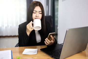 Asian woman working and drink coffee in home with laptop computer smile and happy work. Work from home concept.