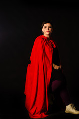 beautiful woman red cloak with red flowers roses in studio. Woman Red Riding Hood. Dramatic and fantastic shooting,fashionable toning. Like a princess