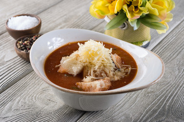 Delicious soup with cheese and meat in a restaurant on a white wooden table