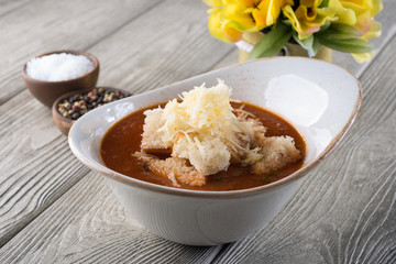 Delicious soup with cheese and meat in a restaurant on a white wooden table