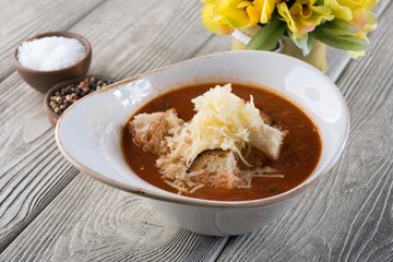 Delicious soup with cheese and meat in a restaurant on a white wooden table