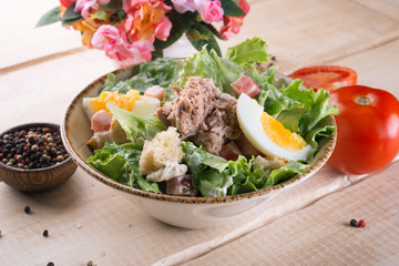 Fresh salad with greens, vegetables, onions and pepper stands on the table in the restaurant