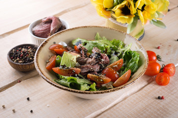 Fresh salad with greens, vegetables, onions and pepper stands on the table in the restaurant