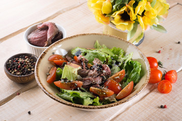 Fresh salad with greens, vegetables, onions and pepper stands on the table in the restaurant