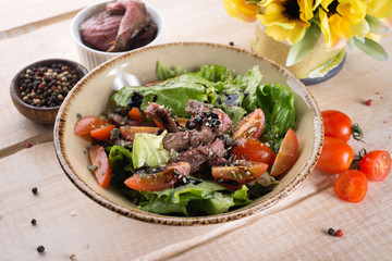 Fresh salad with greens, vegetables, onions and pepper stands on the table in the restaurant