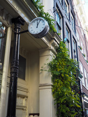 Fototapeta na wymiar Vintage clock walled mounted outside a shop in Amsterdam