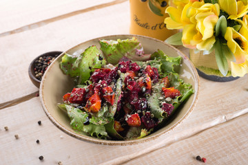 Fresh salad with greens, vegetables, onions and pepper stands on the table in the restaurant