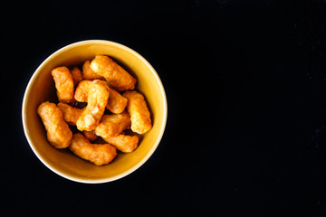 Closeup seasoned chili chicken snack in the ceramic bowl isolated on black background - food concept.