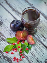 fresh plums juice on a white wooden background