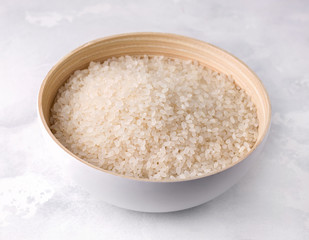 Fototapeta na wymiar Raw rice in a bamboo bowl on a concrete background.