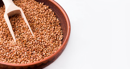 Buckwheat in a clay bowl close-up on a white background. Copy space. Banner