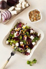 Vegetarian salad with beets and feta. Served in a square bowl. Top view.