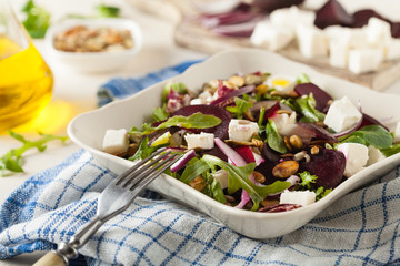 Vegetarian salad with beets and feta. Served in a square bowl. Front view.
