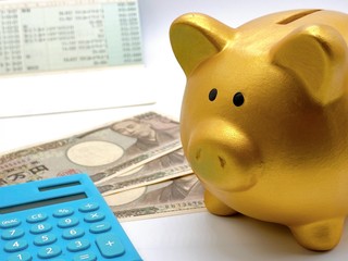 豚の貯金箱と電卓と通帳とお金