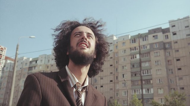 A  Hairy and Bearded Office Guy Leaned Over and Got Up when He Wondering to See Something Interesting While The Birds Flew Over Him.