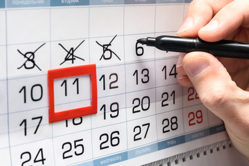 Hand crosses out the next day on the wall calendar