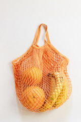 Obraz premium Zero waste. Orange bright string bag with fruit on a white background. Eco concept. Place for text. Lifestyle. Flat lay