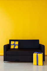 black sofa with gifts in the interior of the yellow room - obrazy, fototapety, plakaty