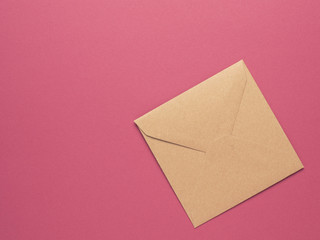 An envelope made from recycled paper on a red background with copy space