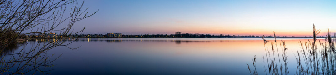 A panorama photo during the Blue hour on a allmost windless evening with a smooth lake Zoetermeerse Plas, Netherlands