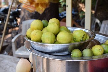 Stock photo of fresh juicy yellow lemons kept in steel bowl or container in the street juice center...