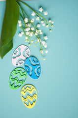 Floral blue background with fresh flowers. Spring greeting card for Easter. A bouquet of lily of the valley and a gift, eggs