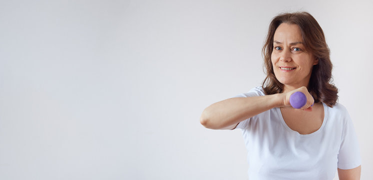 Senior Woman At Home Working Out With Dumbbells..Banner With Copy Space.