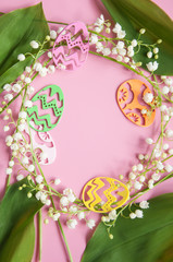 Floral pink background with fresh flowers. Spring greeting card for Easter. A bouquet of lily of the valley and a gift, eggs