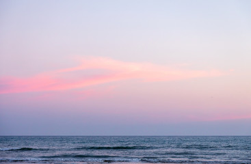 Pink cloud at sunset over an empty, tranquil sea on the south coast of England.
