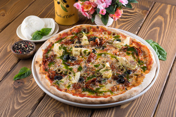 Delicious pizza with cheese, tomatoes, olives and greens