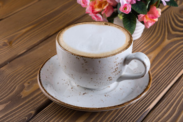 A cup of coffee latte stands on a wooden table